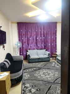 アンマンにあるشقة فاخرة مع مطلの紫色のカーテンとソファ付きのリビングルーム