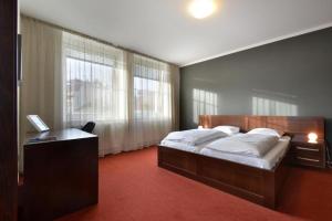 a bedroom with a bed and a desk and windows at Hotel Palác in Olomouc