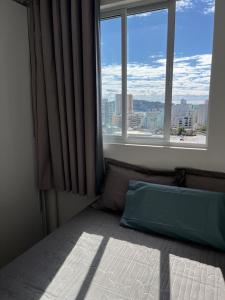 um quarto com uma cama e uma grande janela em Apartamento à 400m do mar em Itapema