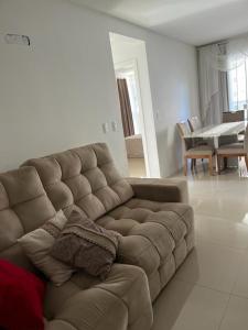 伊塔佩馬的住宿－Apartamento à 400m do mar，客厅配有一张棕色沙发,配有一张桌子