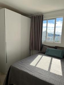 um quarto com uma cama grande e uma janela em Apartamento à 400m do mar em Itapema