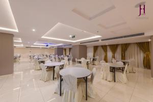 a banquet hall with tables and white chairs at Manazel Al Zaireen Hotel in Makkah