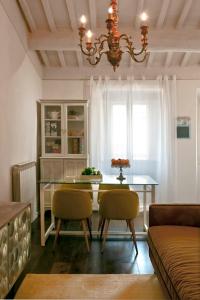 ein Esszimmer mit einem Tisch, Stühlen und einem Kronleuchter in der Unterkunft Ginevra Suite in Cortona