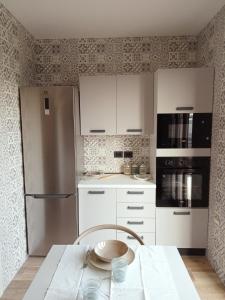 uma cozinha com um frigorífico de aço inoxidável e armários brancos em Le Colline Del Conero em Monte Gallo