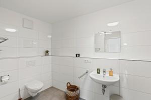 a white bathroom with a toilet and a sink at SEEauszeit in direkter Seenähe in Friedrichshafen +13 photos