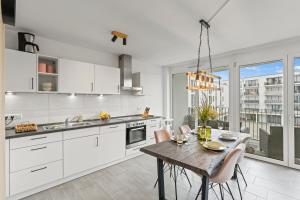 a kitchen with white cabinets and a wooden table at SEEauszeit in direkter Seenähe in Friedrichshafen