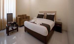 een slaapkamer met een groot bed en een stoel bij FabHotel Prime Lorven in Visakhapatnam