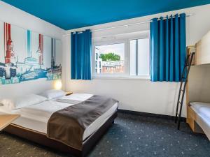 a bedroom with a bed and a window with blue curtains at B&B Hotel Hamburg City-Ost in Hamburg