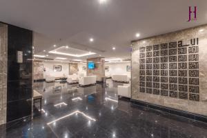a lobby with a waiting room with white chairs and a wall at Manazel Al Zaireen Hotel in Mecca