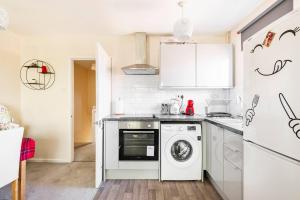 cocina con lavavajillas y lavadora en Immaculate 2 - Bedroom House in Milton Keynes en Milton Keynes