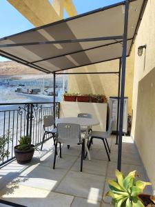 a patio with a table and chairs under a white umbrella at זוהר במדבר ים המלח in Neve Zohar