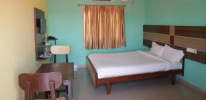 Hotel Sri Murugan Guest House في مهاباليبورام: غرفة نوم بسرير وطاولة ومكتب