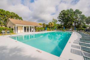a swimming pool with chairs and a house at Calypso Cottage in Bluffton