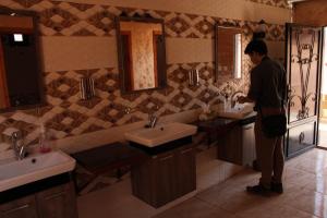 a man standing in a bathroom with two sinks at Walid Bedouin Camp in Wadi Rum