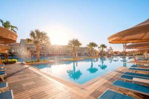 a pool at a resort with chairs and palm trees at Pickalbatros White Beach Resort - Hurghada in Hurghada