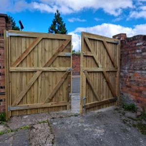 a pair of wooden gates next to a brick wall at Spacious 4 bed house, 7 Beds, Sofabed, Free Private Parking & Wifi in Birkenhead