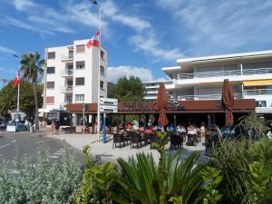 people sitting at tables outside of a building at Appart T3 a 50 m de la plage in Cavalaire-sur-Mer