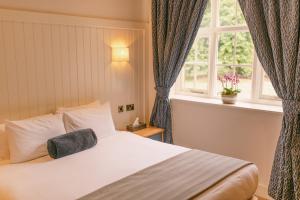 um quarto com uma cama grande e uma janela em The Elvetham Hotel em Farnborough