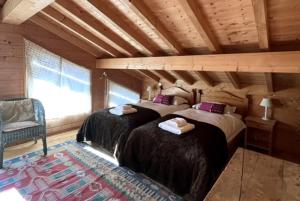 萊熱的住宿－Chalet Pierre, Les Gets，一间卧室配有两张床和一把椅子。