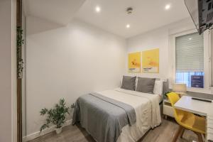 1 dormitorio con cama, escritorio y mesa en AmazINN Places Chamberi, en Madrid