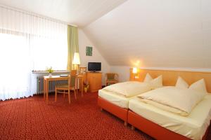 a hotel room with two beds and a desk at Brauereigasthof Rothenbach in Aufseß