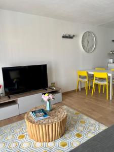 a living room with a tv and a table with yellow chairs at Perle rare à 250m de la plage ! Climatisé avec Parking, balcon & WiFi in Sainte-Maxime