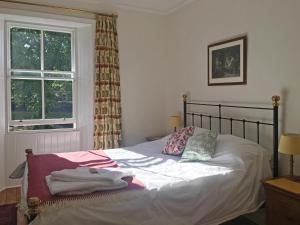 Schlafzimmer mit einem Bett mit weißer Bettwäsche und einem Fenster in der Unterkunft Rutherford House in Town Yetholm