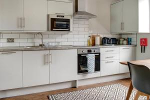 a white kitchen with white cabinets and a table at Beautiful Townhouse Close to Montpellier, Sleeps 6 in Cheltenham