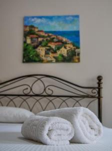 a bed with towels on it with a painting on the wall at Vironas Hotel in Himare