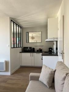 ein Wohnzimmer mit einem Sofa und einer Küche in der Unterkunft Appartement centre Saumur bord de Loire Les marronniers in Saumur