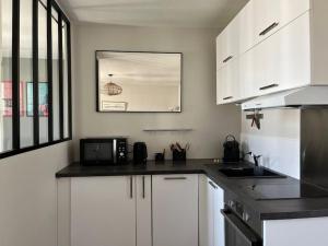 a kitchen with white cabinets and a sink and a microwave at Appartement centre Saumur bord de Loire Les marronniers in Saumur