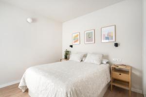 biała sypialnia z białym łóżkiem i drewnianą szafką nocną w obiekcie Room Canalejas w Madrycie