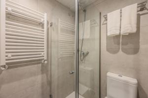 y baño con ducha, aseo y toallas. en AmazINN Places Chamberi, en Madrid