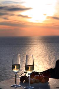 a glass of wine and a plate of food on a beach at Finesse Suites in Oia