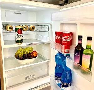 an open refrigerator filled with drinks and a bowl of fruit at BIG 3 separate rooms convenient City HAVEN ! in Bratislava