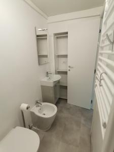 La salle de bains blanche est pourvue de toilettes et d'un lavabo. dans l'établissement Da amènte, à Alassio