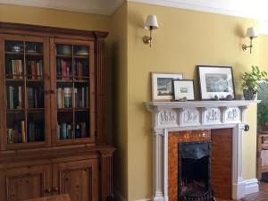 a living room with a fireplace and book shelves at Rutherford House in Town Yetholm