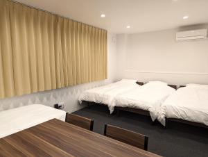 two beds in a room with two tables at Center Point In Kanazawa in Kanazawa