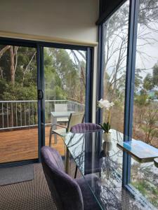 a room with a glass table and chairs on a balcony at Cloud Nine Apartment @ Tamar Ridge in Grindelwald