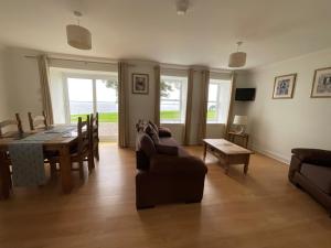a living room with a table and a dining room at Primrose Cottage in Killean