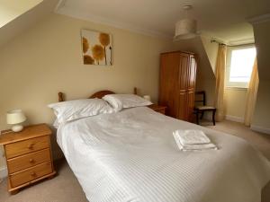 a bedroom with a white bed and a wooden dresser at Primrose Cottage in Killean