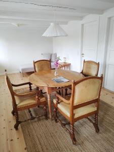 a dining room table with chairs and a vase of flowers on it at Købmandsgården in Ballen