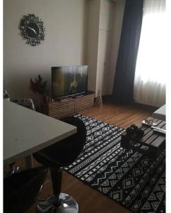 uma sala de estar com uma televisão, uma mesa e um tapete em Eltes Gold Residance em Umraniye