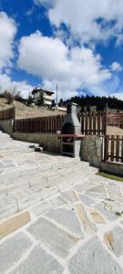un patio de piedra con valla y chimenea en Mountain Pearls Home 9, en Vodata