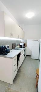 a white kitchen with a sink and a refrigerator at Mountain Pearls Home 9 in Vodata