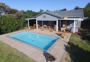 a swimming pool in front of a house at Fiddlewood Beach House in Port Shepstone