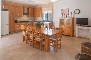 a kitchen with a wooden dining room table and chairs at Es Lliri Blanc in Cala Saona