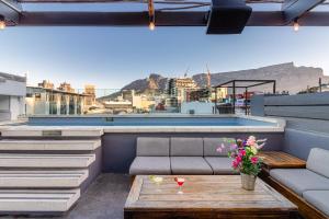 a rooftop patio with a couch and a table with flowers at The Grey Hotel in Cape Town