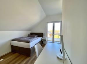 a bedroom with a bed and a desk and a window at Seeglück 1 am Tollensesee in Groß Nemerow