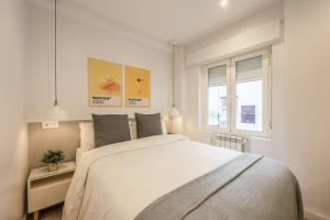 a white bedroom with a large bed and a window at AmazINN Places Chamberi in Madrid
